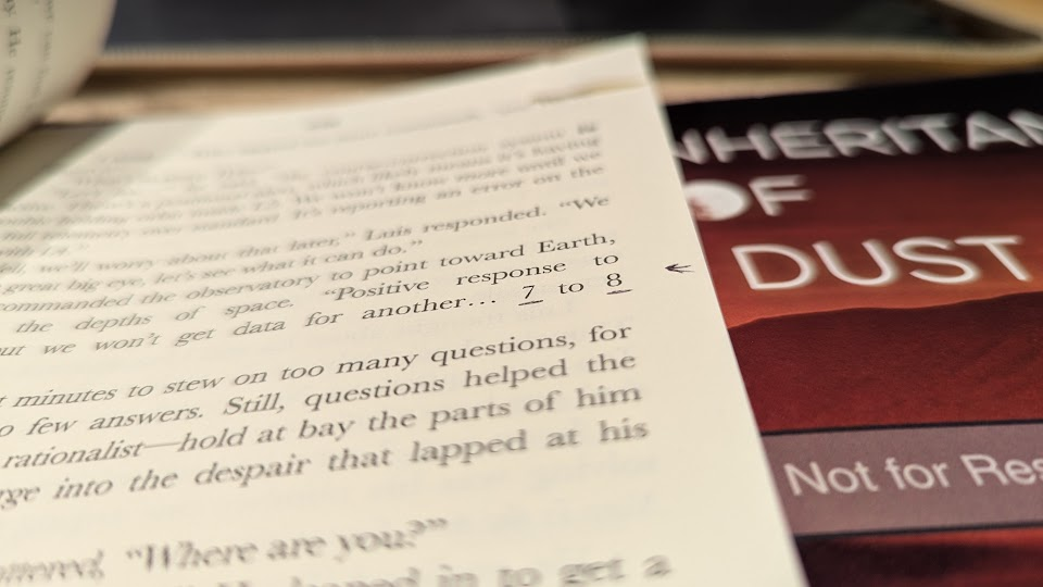 A dog-eared interior page of a proof print showing editing marks. The cover of a second proof print is visible under the marked up copy.